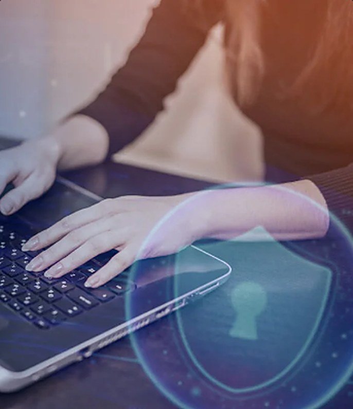 Pessoa digitando em notebook com escudo de proteção de dados em destaque